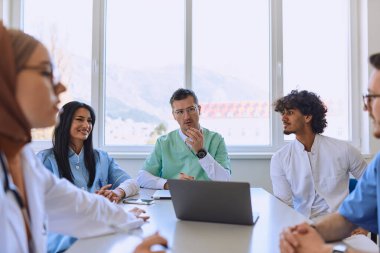 Kendini adamış bir grup doktor ve tıp hemşiresi, meslektaşlarının bir sağlık merkezindeki çalışma planlarını dikkatle dinliyor, işbirliğini teşvik ediyor ve yüksek kaliteli hasta bakımı sağlıyorlar.. 