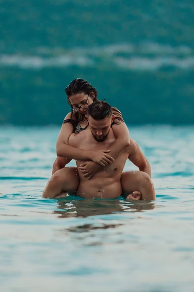 stock image A romantic young couple sharing a passionate kiss amidst the serene beauty of the ocean at sunset