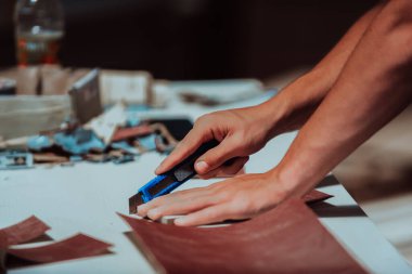 Ahşap işçiliği sektöründe çalışkan bir işçi, ahşap cilalama işlemi için titizlikle kağıt keserken, malzemelerin hazırlanmasında dikkat ve hassasiyet gösterirken görülüyor.