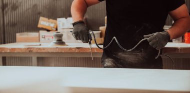 Ahşap işçiliği sektöründeki kendini işine adamış bir işçi, son aşamada titizlikle temizlenmiş ahşap ürünleri kullanmak için sıkıştırılmış hava kullanır. Bu da zanaatkarlığın detaylarına hassasiyet ve dikkat göstermektedir.