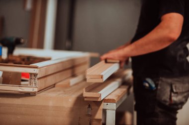 Ahşap işçiliği sektöründeki yetenekli bir işçi modern makineleri işlemek ve piyasaya ahşap kapılar hazırlamak için kullanmakta, geleneksel işçiliğin kusursuz bir karışımını sergilemekte ve kesmektedir.