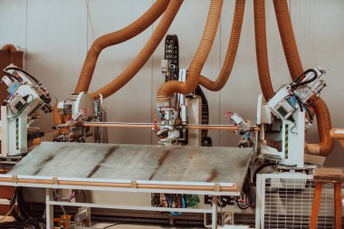 Modern bir ahşap işleme tesisinde, modern bir CNC makinesinde kusursuz bir hassas teknoloji ve geleneksel zanaatkarlık sergileniyor, çeşitli bir dizi üretmek için uyum içinde çalışıyor.