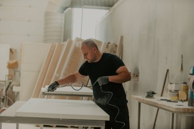 Ahşap işçiliği sektöründeki kendini işine adamış bir işçi, son aşamada titizlikle temizlenmiş ahşap ürünleri kullanmak için sıkıştırılmış hava kullanır. Bu da zanaatkarlığın detaylarına hassasiyet ve dikkat göstermektedir.