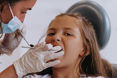 Neşeli bir kız modern bir pediatrik diş hekimliğinde diş muayenesinden geçiyor.. 