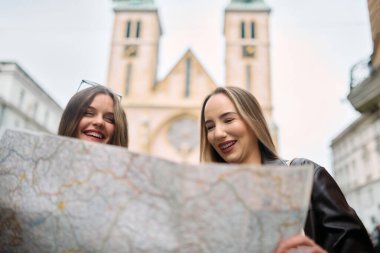 İki kadın turist, ellerinde haritayla şehrin hareketli caddelerinde gezintilerini planlarken, bavullarıyla çevrili, canlı bir tartışma içindeler.