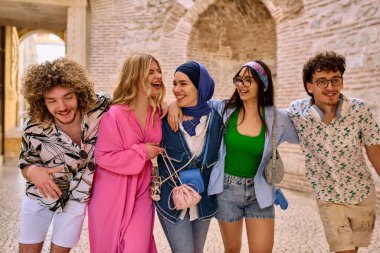 Yaz kıyafetleri içinde çeşitli turist grupları, geniş tebessümleriyle turistik şehirde geziniyor, gezintilerinin tadını çıkarıyorlar.. 