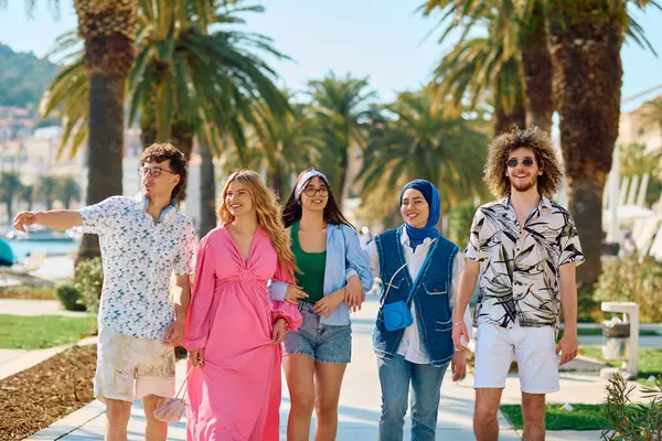 stock image A diverse group of tourists, dressed in summer attire, strolls through the tourist city with wide smiles, enjoying their sightseeing adventure. 