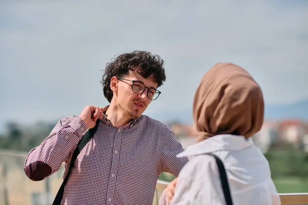 stock image After a day at the office, a business man engages in conversation with his Muslim colleague wearing a hijab. 