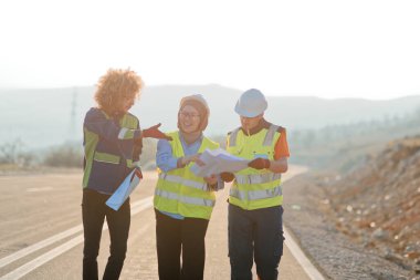 Mühendis ve işçilerden oluşan bir ekip, yenilenebilir enerjinin verimli bir şekilde üretilmesini sağlamak için birlikte çalışan modern bir rüzgâr çiftliğinde rüzgar türbini projesini denetliyor.. 