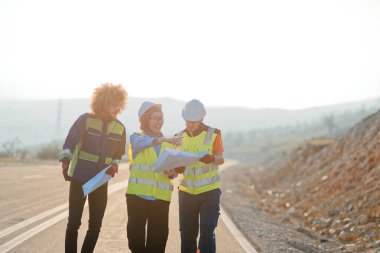 Mühendis ve işçilerden oluşan bir ekip, yenilenebilir enerjinin verimli bir şekilde üretilmesini sağlamak için birlikte çalışan modern bir rüzgâr çiftliğinde rüzgar türbini projesini denetliyor.. 