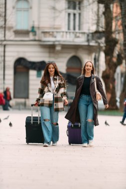 İki kadın turist bir Avrupa şehrini keşfediyor, bavullarını çekerek büyüleyici caddelerde geziniyorlar, kendilerini seyahat yerlerinin kültürüne ve güzelliğine kaptırıyorlar..
