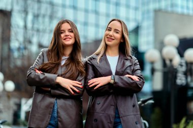 İki başarılı iş kadını şirket binalarının önünde gururla poz veriyor, başarılarını kutluyor ve diğerlerine ilham veriyor.. 