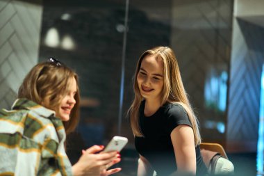 İki arkadaş en sevdikleri kafede buharlı kahve içerken bir an iletişim ve kahkaha paylaşıyorlar.. 