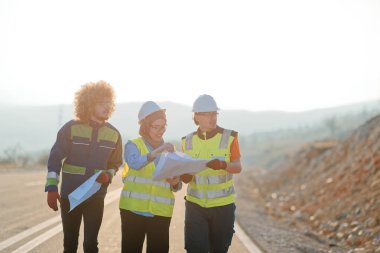 Mühendis ve işçilerden oluşan bir ekip, yenilenebilir enerjinin verimli bir şekilde üretilmesini sağlamak için birlikte çalışan modern bir rüzgâr çiftliğinde rüzgar türbini projesini denetliyor.. 