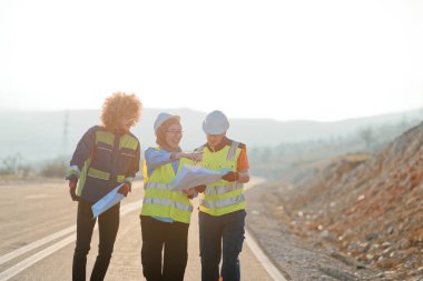 Mühendis ve işçilerden oluşan bir ekip, yenilenebilir enerjinin verimli bir şekilde üretilmesini sağlamak için birlikte çalışan modern bir rüzgâr çiftliğinde rüzgar türbini projesini denetliyor.. 