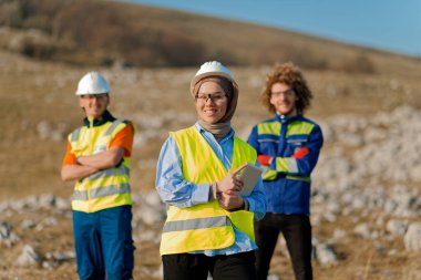 Mühendis ve işçilerden oluşan bir ekip, yenilenebilir enerjinin verimli bir şekilde üretilmesini sağlamak için birlikte çalışan modern bir rüzgâr çiftliğinde rüzgar türbini projesini denetliyor.. 