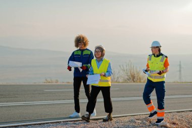 Mühendis ve işçilerden oluşan bir ekip, yenilenebilir enerjinin verimli bir şekilde üretilmesini sağlamak için birlikte çalışan modern bir rüzgâr çiftliğinde rüzgar türbini projesini denetliyor.. 