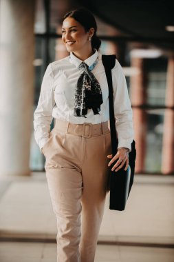 Zarif bir Latin iş kadını, çantasıyla modern ofisinde rahatça dolaşır ve kararlılığını belli eder.. 