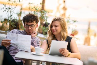 A dynamic business couple sits in a cafe, engrossed in paperwork, utilizing tablets, and engaging in thoughtful discussions as they strategize and plan their entrepreneurial ventures clipart