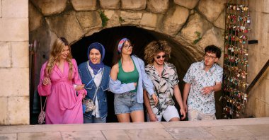 Yaz kıyafetleri içinde çeşitli turist grupları, geniş tebessümleriyle turistik şehirde geziniyor, gezintilerinin tadını çıkarıyorlar.. 