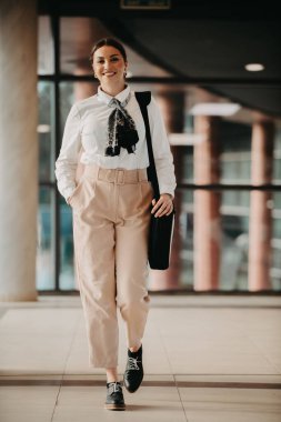 Zarif bir Latin iş kadını, çantasıyla modern ofisinde rahatça dolaşır ve kararlılığını belli eder.. 