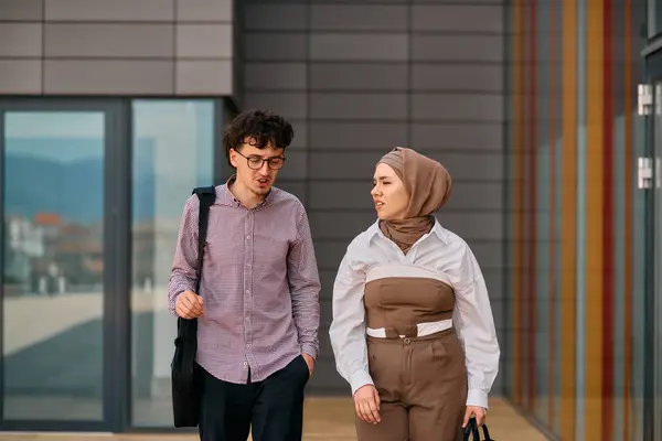 stock image After a day at the office, a business man engages in conversation with his Muslim colleague wearing a hijab. 
