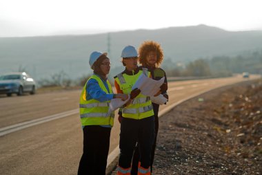 Mühendis ve işçilerden oluşan bir ekip, yenilenebilir enerjinin verimli bir şekilde üretilmesini sağlamak için birlikte çalışan modern bir rüzgâr çiftliğinde rüzgar türbini projesini denetliyor.. 