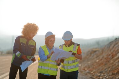 Mühendis ve işçilerden oluşan bir ekip, yenilenebilir enerjinin verimli bir şekilde üretilmesini sağlamak için birlikte çalışan modern bir rüzgâr çiftliğinde rüzgar türbini projesini denetliyor.. 
