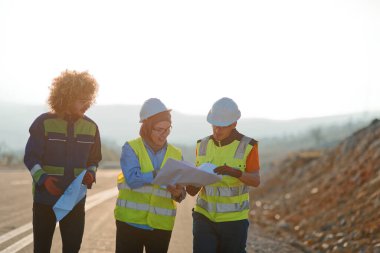 Mühendis ve işçilerden oluşan bir ekip, yenilenebilir enerjinin verimli bir şekilde üretilmesini sağlamak için birlikte çalışan modern bir rüzgâr çiftliğinde rüzgar türbini projesini denetliyor.. 
