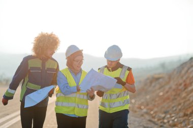 Mühendis ve işçilerden oluşan bir ekip, yenilenebilir enerjinin verimli bir şekilde üretilmesini sağlamak için birlikte çalışan modern bir rüzgâr çiftliğinde rüzgar türbini projesini denetliyor.. 