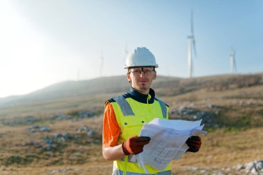 Elektrik üretimi için rüzgar türbininin kağıt projesini elinde tutan bir mühendis.