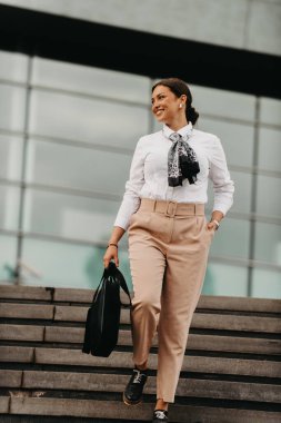 Şık bir Latin iş kadını şehrin hareketli sokaklarında elinde evrak çantası ve yüzünde kararlı bir gülümseme ile rahatça yürüyor.. 