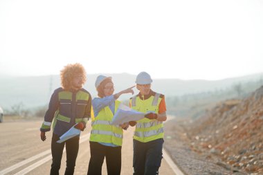 Mühendis ve işçilerden oluşan bir ekip, yenilenebilir enerjinin verimli bir şekilde üretilmesini sağlamak için birlikte çalışan modern bir rüzgâr çiftliğinde rüzgar türbini projesini denetliyor.. 