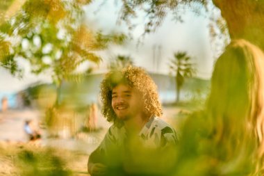 Bir grup arkadaş plajda toplanıp müzik, kahkaha ve birlikteliğin sıcaklığıyla dolu neşeli anları paylaşıyorlar. Gençler sahilde eğleniyor.