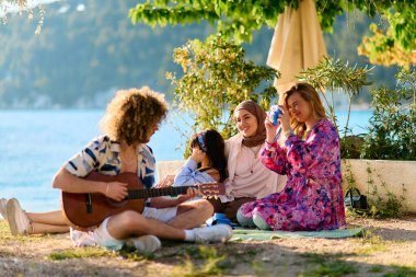 A group of friends gather on the beach sharing joyful moments filled with music, laughter and the warmth of togetherness, teenagers having fun on the beach clipart