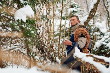 A determined mountaineer sails through a peaceful snow-covered forest, equipped with a rope and a backpack, embodying the spirit of adventure in the heart of winter.  clipart