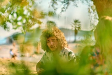 Bir grup arkadaş plajda toplanıp müzik, kahkaha ve birlikteliğin sıcaklığıyla dolu neşeli anları paylaşıyorlar. Gençler sahilde eğleniyor.