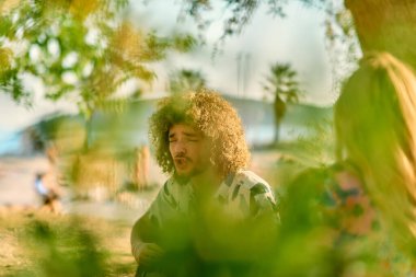 Bir grup arkadaş plajda toplanıp müzik, kahkaha ve birlikteliğin sıcaklığıyla dolu neşeli anları paylaşıyorlar. Gençler sahilde eğleniyor.