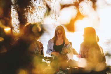 Bir grup arkadaş plajda toplanıp müzik, kahkaha ve birlikteliğin sıcaklığıyla dolu neşeli anları paylaşıyorlar. Gençler sahilde eğleniyor.