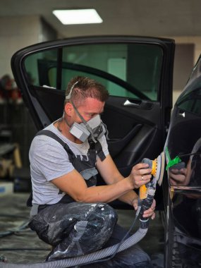 Yetenekli bir oto boyacı, bir arabayı resme hazırlamak için titizlikle cilalıyor, atölyede ustalık ve ustalık gösteriyor.