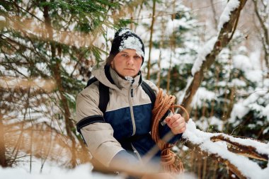 Kararlı bir dağcı, kışın kalbinde macera ruhunu somutlaştıran bir halat ve sırt çantasıyla donatılmış, karla kaplı huzurlu bir ormanda yelken açar.. 