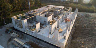 Modern bir binanın devam eden yapısını gösteren bir insansız hava aracı tarafından çekilen hava görüntüsü, yapıdaki çalışmaları, iskeleyi ve mekaniği vurguluyor.