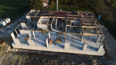 Modern bir binanın devam eden yapısını gösteren bir insansız hava aracı tarafından çekilen hava görüntüsü, yapıdaki çalışmaları, iskeleyi ve mekaniği vurguluyor.