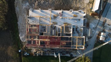 Modern bir binanın devam eden yapısını gösteren bir insansız hava aracı tarafından çekilen hava görüntüsü, yapıdaki çalışmaları, iskeleyi ve mekaniği vurguluyor.