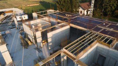 Modern bir binanın devam eden yapısını gösteren bir insansız hava aracı tarafından çekilen hava görüntüsü, yapıdaki çalışmaları, iskeleyi ve mekaniği vurguluyor.