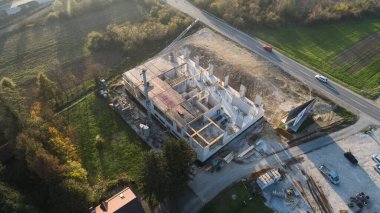 Modern bir binanın devam eden yapısını gösteren bir insansız hava aracı tarafından çekilen hava görüntüsü, yapıdaki çalışmaları, iskeleyi ve mekaniği vurguluyor.