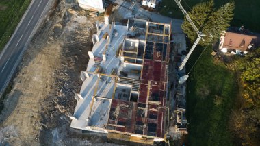 Modern bir binanın devam eden yapısını gösteren bir insansız hava aracı tarafından çekilen hava görüntüsü, yapıdaki çalışmaları, iskeleyi ve mekaniği vurguluyor.