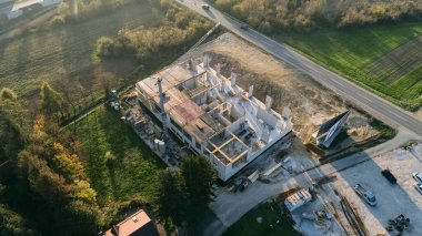 Modern bir binanın devam eden yapısını gösteren bir insansız hava aracı tarafından çekilen hava görüntüsü, yapıdaki çalışmaları, iskeleyi ve mekaniği vurguluyor.