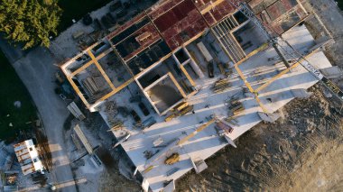 Modern bir binanın devam eden yapısını gösteren bir insansız hava aracı tarafından çekilen hava görüntüsü, yapıdaki çalışmaları, iskeleyi ve mekaniği vurguluyor.