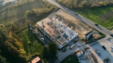 Modern bir binanın devam eden yapısını gösteren bir insansız hava aracı tarafından çekilen hava görüntüsü, yapıdaki çalışmaları, iskeleyi ve mekaniği vurguluyor.